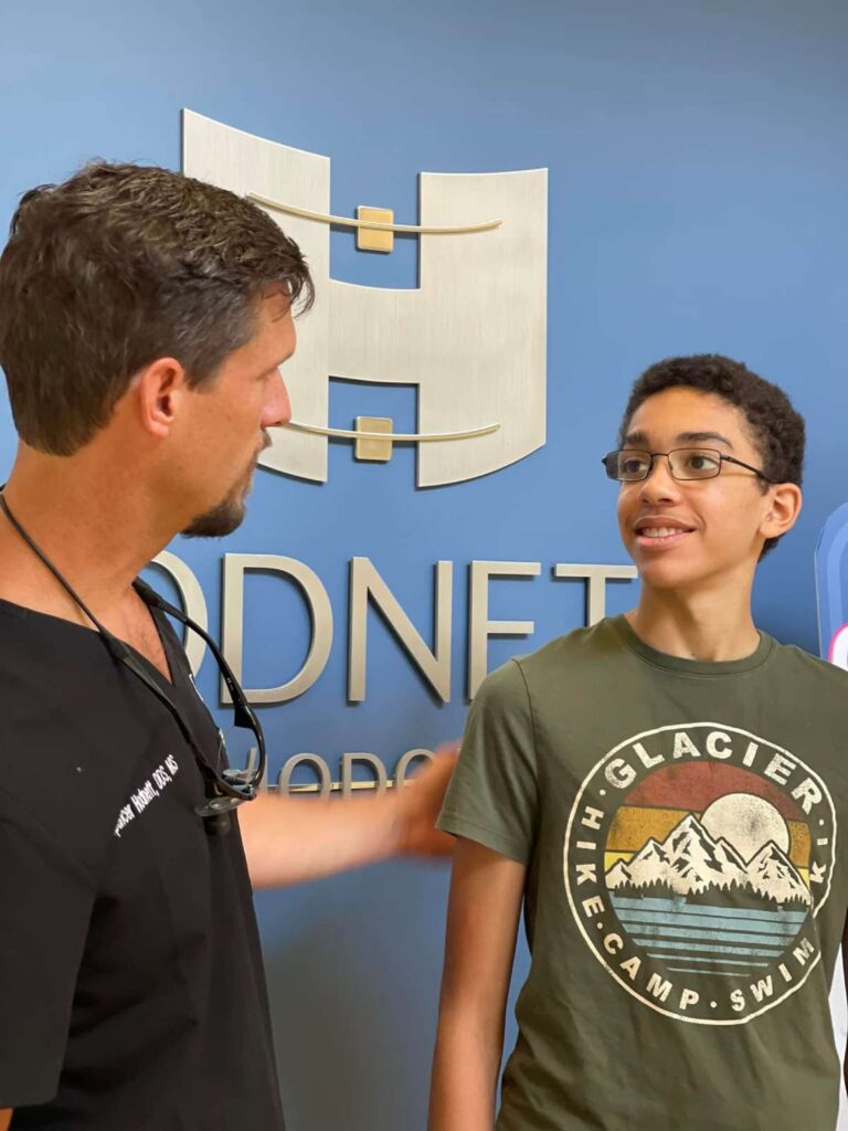 A man and boy talking in front of a sign.